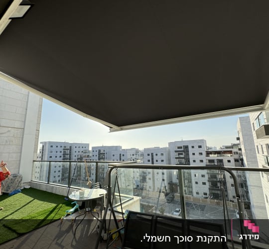 סוכך שחור תלוי מעל מרפסת עם נוף עירוני